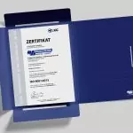 ISO 9001:2015 Zertifikat für Qualitätsmanagement, ausgestellt an Brüggemann Spedition + Logistik GmbH & Co. KG, auf Schreibtisch in einer Präsentationsmappe