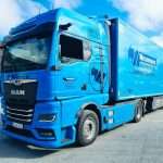 Blauer elektrischer LKW der Spedition Wesemann mit Kühlaufbau steht auf einem Betriebshof unter blauem Himmel. Auf dem Fahrerhaus ist der Schriftzug „100 % elektrisch“ zu sehen, das Fahrzeug trägt das Wesemann Logo und steht für nachhaltige Lebensmittellogistik.